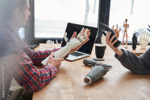 Male and female colleagues holding bionic prosthesis limbs and discussing it