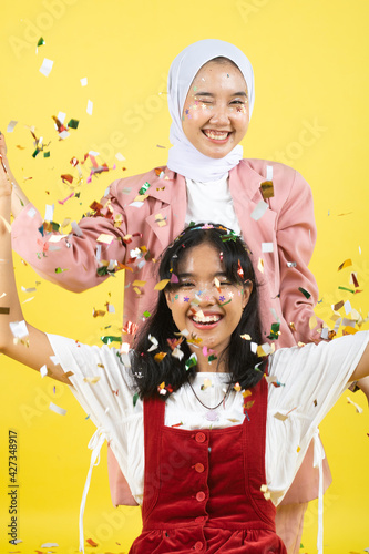 Closeup portrait of two young beautiful asian woman isolated on yellow background.