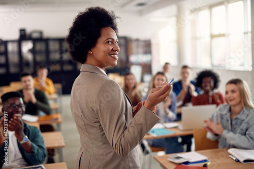 Happy black techer getting applause from her students after giving them a lecture at the university.