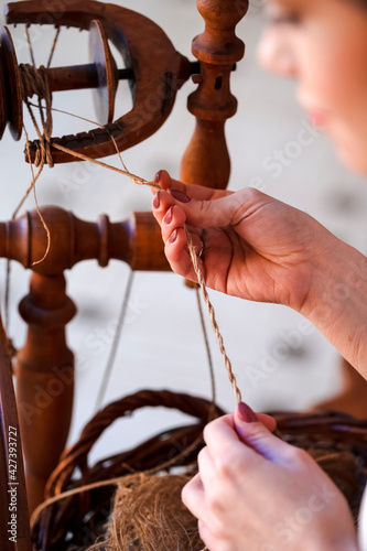 Portrait of Young Caucasian Woman Spinning Yarn in Retro Dress In Rural Environment.