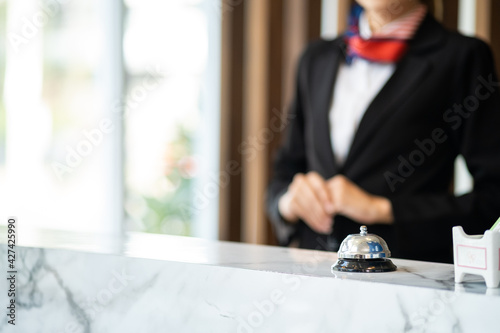Close up bell in luxury modern reception hotel desk with the blurred reception employee preparing for welcome new customer