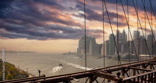 Brooklyn Bridge and Manhattan New York USA against cloudy sky at sunset