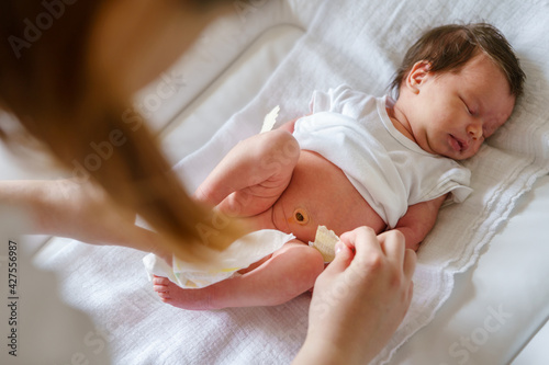 Top view on caucasian baby sleep while her mother is changing diapers and clothes newborn lying on the bed at home - parenting childhood new life and growing up concept