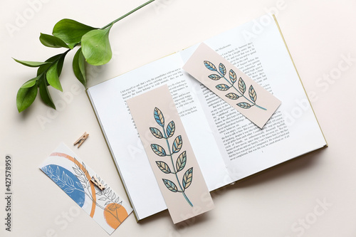 Book with bookmarks and branch on light background