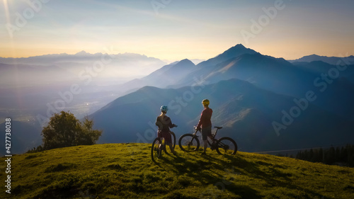 Two females on mountain bikes talking and looking at beautiful sunset