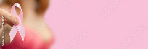 Woman holds pink ribbon in her hands - Symbol of the fight against breast cancer. Panorama