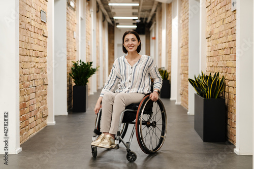 White young woman smiling while sitting in wheelchair at office