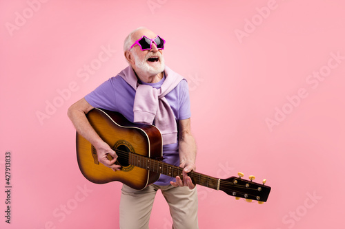 Photo portrait of funky happy grandpa playing guitar wearing star sunglass isolated on pastel pink color background