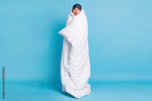 Full length photo portrait of scared man wrapped in duvet isolated on vivid blue colored background