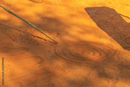 aboriginal people creating shapes with red sand on the ground in aboriginal art style. Northern Territory, Australia