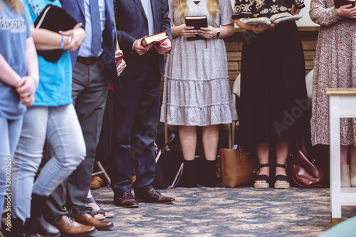 Group of people holding Bible books and praying during a congregation in a church