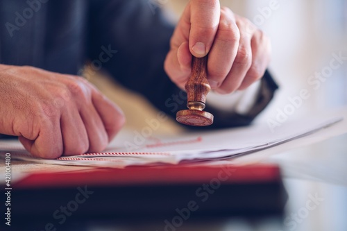 Close-up of the hand of a notary who manually stamps the certificate.