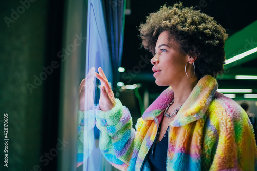 Young mixed race curly hair woman interacting with touchscreen terminal