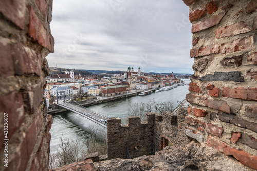 Blick durch eine Schießscharte in der Burgmauer der Feste Oberhaus bei der drei Flüsse Stadt Passau mit Blick auf die Stadt den Fluss Donau auf das Rathaus und den Dom, Deutschland