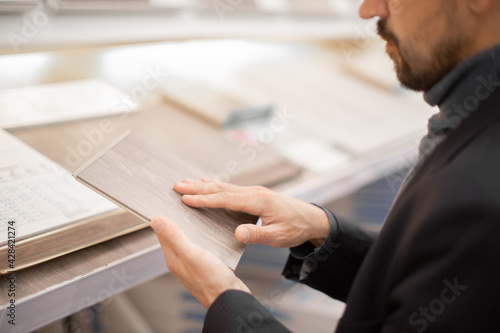 .Middle age man choosing floor laminate for his home. Difficult decision which to buy