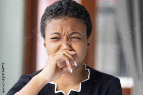 African woman having runny nose or covering her nose for bad smell, concept of stink thing, bad breath, unpleasant smell, odor, bad smell, young adult black African woman model