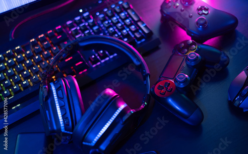 gamer work space concept, top view a gaming gear, mouse, keyboard, joystick, headset with rgb color on black table background.