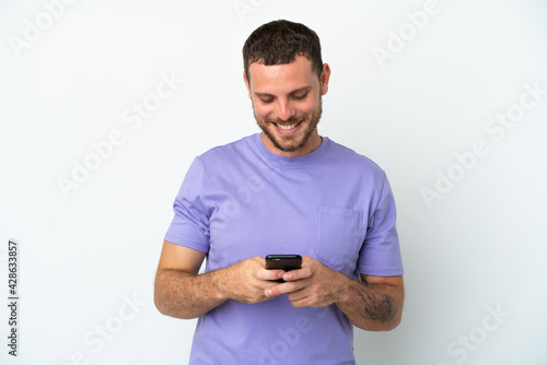 Young Brazilian man isolated on white background sending a message with the mobile