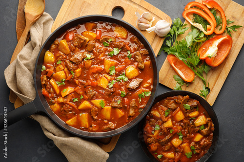 Goulash, beef stew with vegetables in tomato sauce. Top view. Dark (black) background.
