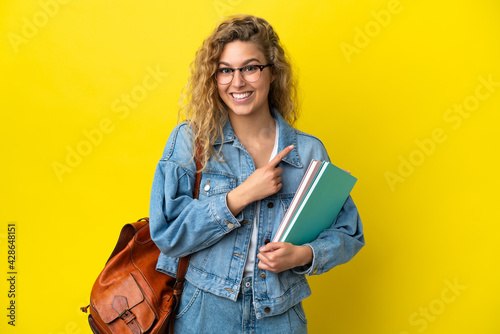 Young student caucasian woman isolated on yellow background pointing to the side to present a product