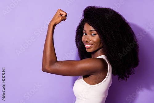 Profile photo of charming positive dark skin girl arm flex show biceps isolated on violet color background