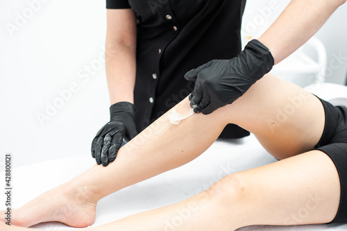 Midsection of female therapist waxing customer's leg at beauty spa