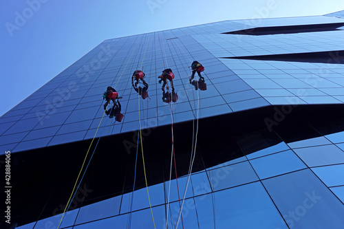 Window cleaners abseiling down the exterior of an office building in Rome, Italy.