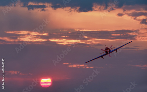 Beautiful colorful sunset landscape and vintage light propeller plane flying 
