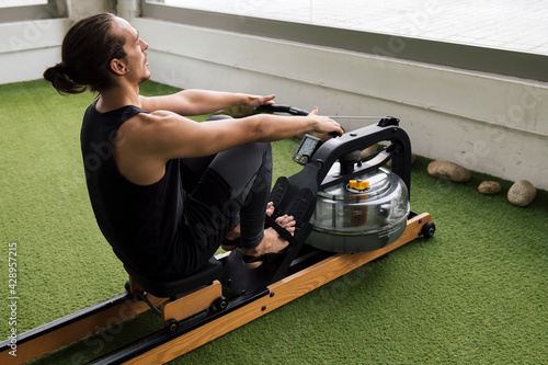 sportsman training at gym on water rowing machine