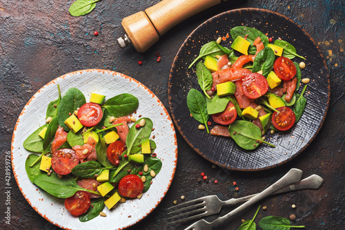 Healthy salad with fresh baby spinach, cherry tomatoes, avocado and salmon fish