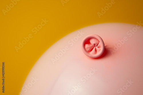 An image of a pink balloon on a yellow background. Metaphor prevention of hemorrhoids, anus hygiene, proctology, bowel health. 