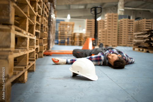 Injury at work. Warehouse worker lying unconscious on the concrete floor after the fall.