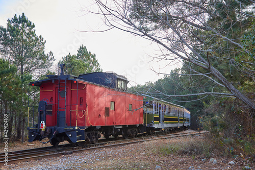 Old fashioned red caboose on the end of a train going around the bend