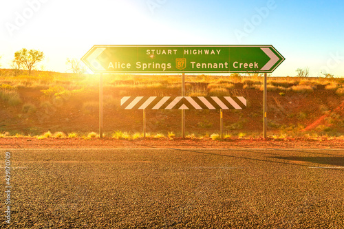 Northern Territory, Australia Outback. Stuart Highway signboard direction Alice Springs or Tennant Creek. Tourism in Central Australia, Red Centre. Sun with rays at sunset.