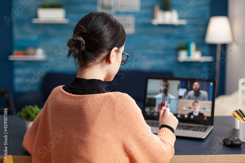 Young woman using laptop computer talking with collegue about school communication project during university videocall meeting. Student on remote e-learning education during coronavirus quarantine