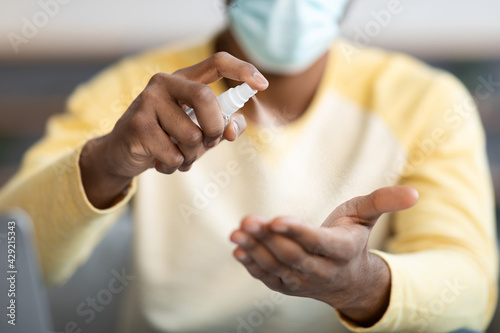 Closeup of black guy hands with disinfectant mist spray