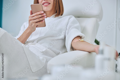 Beautiful Caucasian woman sitting in armchair during medicine procedure in spa salon