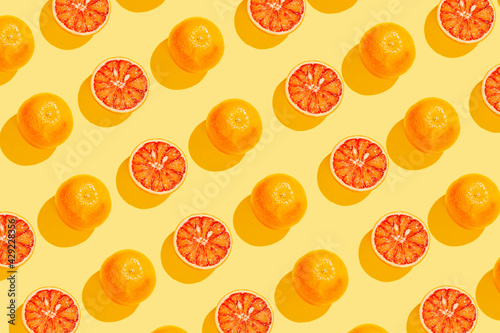 Creative pattern made with blood orange on yellow background. Summer fruit concept. Minimal style. Sunlit flat lay. Top view