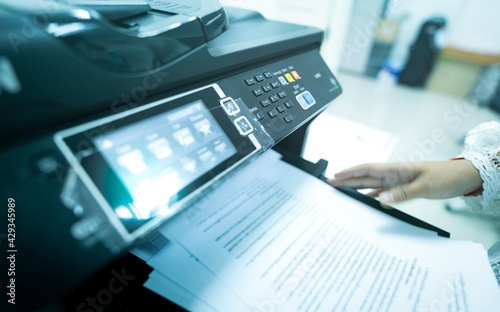 Office worker print paper on multifunction laser printer. Copy, print, scan, and fax machine in office. Modern print technology. Photocopy machine. Document and paper work. Scanner. Secretary work.