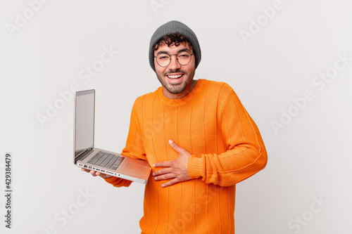 nerd man with computer laughing out loud at some hilarious joke, feeling happy and cheerful, having fun