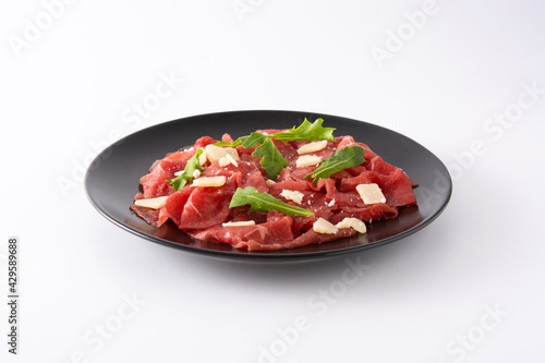 Marbled beef carpaccio on black plate isolated on white background