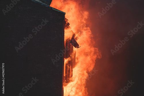 Massive large blaze fire in the city, brick factory building on fire, hell major fire explosion flame blast, with firefighters team firemen on duty, arson, burning house damage destruction