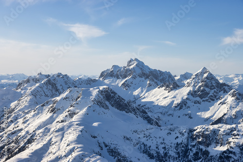 Aerial View from Airplane of Blue Snow Covered Canadian Mountain Landscape in Winter. Bright Sunny Sky. Tantalus Range near Squamish, North of Vancouver, British Columbia, Canada. Authentic Image.