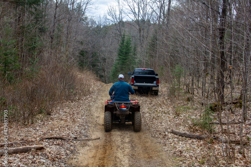 Man riding ATV towards Truck in a Forest