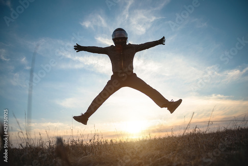 A happy motorbike in the helmet is jumping among a field at sunset. Freedom.