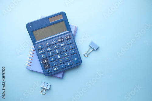 Close up of blue calculator and notepad on color background 