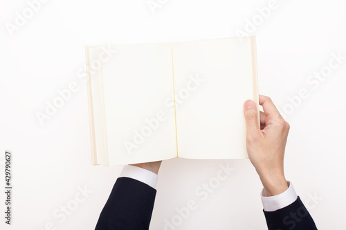 何も書かれていない白紙のページが開かれた本を両手で持つ人
