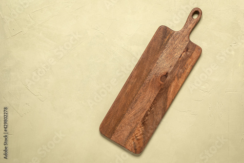 Wooden long empty cutting board on a beige concrete background. Top view, flat lay.