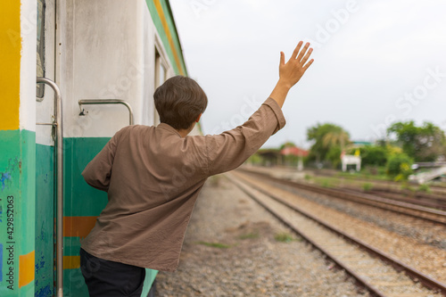 Handsome Young Asian man hand to say hello or goodbye to friend on train, Waving Goodbye