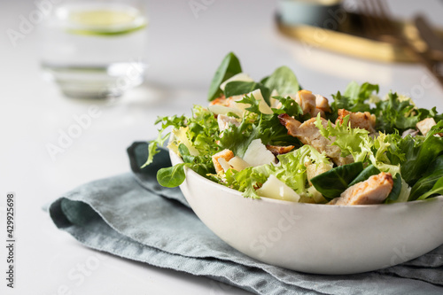 Cesar salad plate served on restaurant table. Healthy salad with different lettuce, chicken, parmesan cheese and croutons.